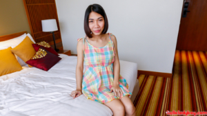 Sexy Pattaya Ladyboy sitting in bed wearing sun dress